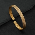 Goldenes Titanstahl-Armband mit gewebter Textur auf dunkelgrauem Stein-Hintergrund - Gold