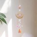 Golden moon and sun crystal suncatcher with iridescent teardrop pendant hanging by a window - Pink