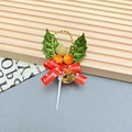Close-up of Christmas cake topper featuring holly leaves, golden bell, and red ribbon bow - Leaves-2005