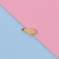 Macro shot of oval golden stainless steel pendant charm with S.Steel engraving - 18K Gold Plated