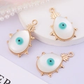 Detail of three pineapple-shaped devil's eye pendants with white stones on a display - Evil Eye