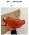 Detailed close-up of orange nylon belt bag with adjustable strap in casual outdoor setting - Orange