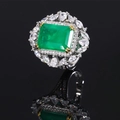 Rectangle emerald ring with marquise diamond halo and gold prongs on black reflection - Emerald