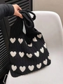 Black knitted underarm tote bag featuring white heart patterns and cable knit texture - Black