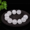 Polished white translucent cat-eye jade beads arranged on a dark decorative round tray - White Crystal