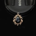 Macro d'un pendentif en pierre noire en forme de larme dans un cadre ornemental en alliage doré - Noir