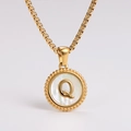 Detail of gold necklace featuring a round white shell pendant with letter Q engraving - Letter Q