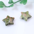 Polished star-shaped unakite stones with green and pink patterns on white surface - Unakite