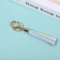 Detailed view of a rainbow tassel keychain with gold metal clasp on a green background - Rainbow