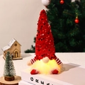 Détail d'un gnome de Noël à paillettes rouges avec barbe lumineuse LED sur des livres - Rouge