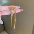 Detalle de pendientes largos dorados con borlas y cadena de serpiente y bolas lisas - Dorado