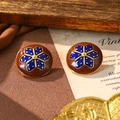 Gros plan de boucles d'oreilles vintage en émail avec motifs floraux sur tissu brun - Style Fleur Bleue Base Marron (E4-20472D-6500)
