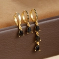 Macro shot of three gold drop earrings with black zircon stones on leather backdrop - Gold-Black