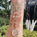 Detail of silver butterfly suncatcher with pink crystals and moon charms in natural light - Sunstone