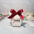 Makroaufnahme der weißen Geschenkbox in Trapezform mit dunkelroter Schleife und Love-Print - 6x10x12cm / Rot