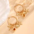 Dettaglio di orecchini a cerchio dorati con pendenti a stella e conchiglia - Stile Ciondolo Oceano Oro Opaco (01 Oro Opaco 9814)