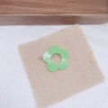 Détail d'une pince à cheveux fleur verte sur tapis de lin avec éclairage de studio naturel - Vert fruit