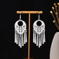 Dettaglio di orecchini etnici argentati con nappe e intricati motivi intagliati - Cilindro Traforato (E7266) / Argento