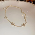 Détail du collier papillon doré avec pavé de diamants étincelants sur une assiette blanche - Papillon / Doré