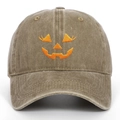 Detailed close-up of orange Jack-o'-lantern pumpkin embroidery on a khaki cotton baseball cap - One Size / Khaki