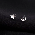 Macro detail of asymmetric S925 sterling silver star and moon stud earrings with mirror finish - Asymmetrical Star Moon / Silver