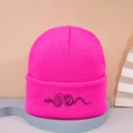 Close-up of bright pink knitted beanie with black snake embroidery on a wide cuff - Embroidered Snake / Rose Red