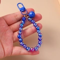 Detail of blue iridescent beaded keychain with metal D-hook and matching round bell - Blue