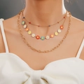 Three-layer gold chain necklace with colorful enamel daisies on a model neck - Triple Layer Gold Enamel Daisy Necklace