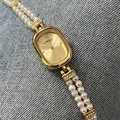 Elegant gold oval quartz watch with double-row pearl bracelet and Roman numerals - Gold Dial Gold Case