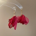 Dettaglio di orecchini a fiore in chiffon rosso con ganci in metallo dorato su supporto - Rosso