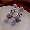 Macro detail of vintage style cat earrings with purple oval stones and silver accents - Retro Cat Drop Style / Purple & Distressed Silver