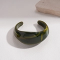 Detailansicht des dunkelgrün marmorierten Resin-Armreifs auf einer strukturierten Oberfläche - Armreif-Olivgrün