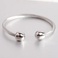 Vue macro d'un bracelet jonc câble en acier inoxydable argenté avec embouts sphériques - Couleur Acier