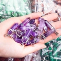 Hand die een paarse amethist kristallen hanger vasthoudt met zilveren oog voor kettingen - Amethist