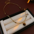 Detail of amber heart pendant on gold beaded necklace inside a premium jewelry gift box - Brown