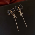 Detail of vintage black bow earrings with long golden tassels on a luxury leather texture - Gold-Black Bowknot