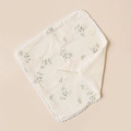 Macro shot of cotton baby bib with vintage floral prints and pom-pom trim detail - Beige And Floral