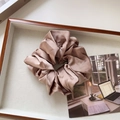 Close-up of champagne satin scrunchie with soft pleats on a wooden display tray - Large / Light Coffee