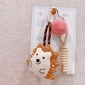 Close-up of a cute plush hedgehog keychain with pink pompom and woven nylon rope strap - Hedgehog