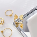 Nahaufnahme der 18K vergoldeten Titanringe mit Schmetterling- und Stern-Motiven - US 6 / Schmetterling