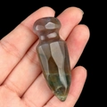Natural hand-carved agate stone dagger ornament held in hand against a black background - India Agate