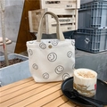 Close-up of white corduroy tote bag with smiley face and khaki canvas handle on wood table - Creamy White Smiley Face