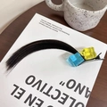 Cosplay hair clip with yellow and blue cubes on dark hair over a white book - Ice Cube Black Brown