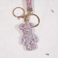 Macro shot of pink and white gradient rhinestone bear keychain with a golden lobster clasp - Mixed Pink