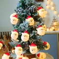 LED Christmas string lights with 3D Santa Claus heads on snowy tree branches - Santa Head
