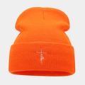 Close-up of bright orange ribbed knit beanie with white Faith cross embroidery detail - Orange Red