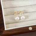 Detail of cream white pearl earrings with gold posts on a beige jewelry display tray - 8mm Pink Light Pearl