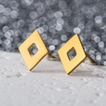 Detailed view of geometric hollow rhombus earrings in gold finish on white texture - Hollow Rhombus / Gold