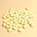 Macro shot of 10mm light yellow heart-shaped polymer clay beads with colorful swirl patterns - Yellow