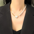 Chique halve ketting halve parel ketting met hart hanger gedragen op een model - Gouden Asymmetrische Parel Hart Stijl